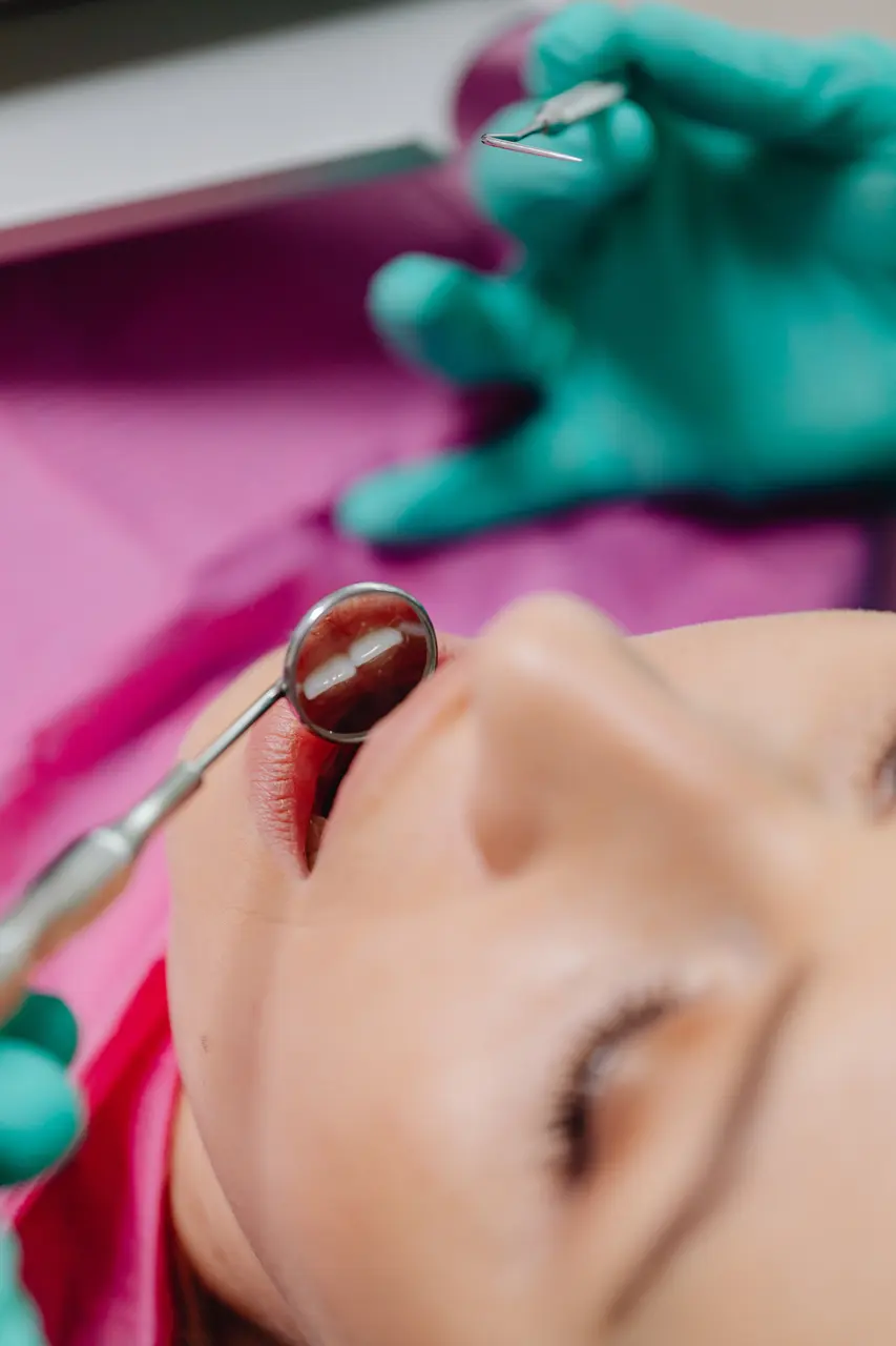 A dental mirror and gloved hands during an examination