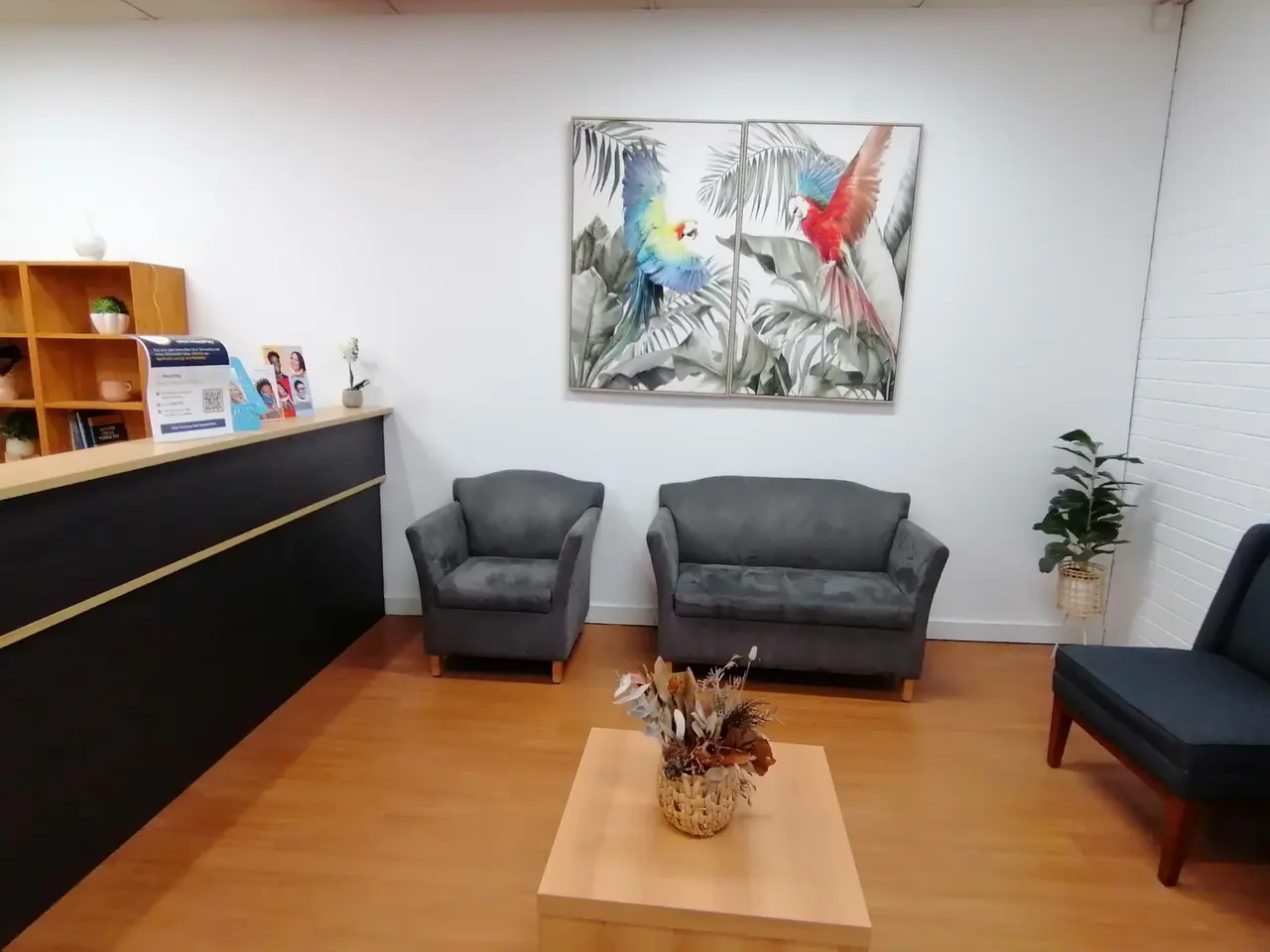 The clinic waiting area, with armchairs, a sofa and a framed parrot artwork